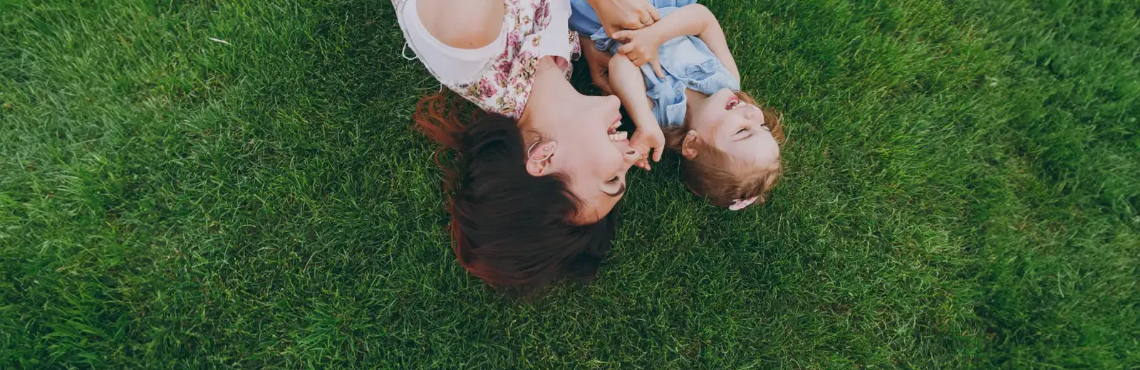 mother daughter laughing laying on lawn